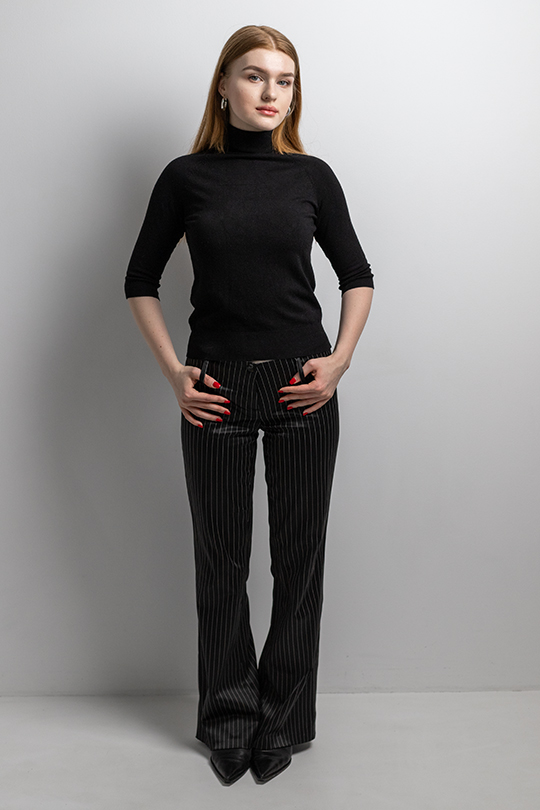 Тотал-блэк образ с черными полосатыми брюками на низкой талии и черной водолазке.